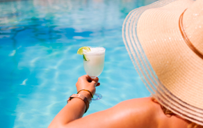 Vrouw met hoed en tropisch drankje in het zwembad