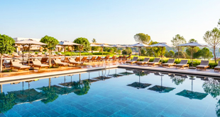 Ligstoelen en parasols omringen zwembad in zonnig resort, Bodrum, Turkije.