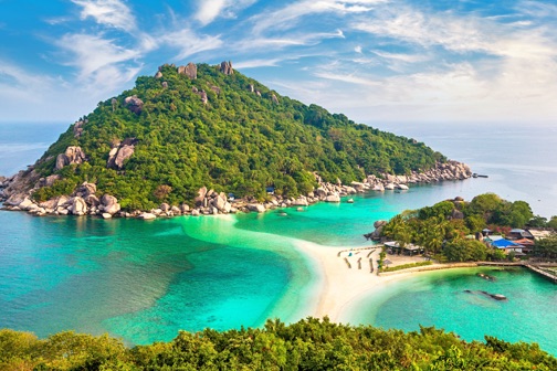 Tropisch eiland in Thailand met groene heuvel, wit zandstrand en ondiep turquoise water dat een natuurlijke baai vormt.