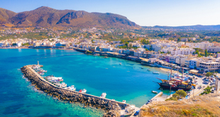 Haven van Chersonissos in Griekenland met blauw water en bergen op de achtergrond voor een jongerenvakantie