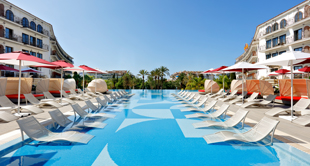 Ligstoelen aan zwembad in resort, omgeven door luxe gebouwen, Mallorca, Spanje.