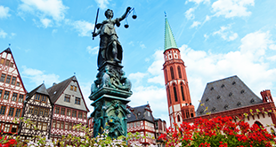 Standbeeld Lady Justice kijkt uit over historische gebouwen in Frankfurt, Duitsland, op een zonnige dag.