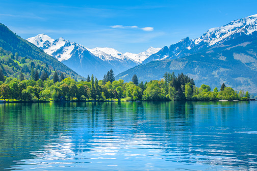 Kristalhelder meer met besneeuwde bergen op de achtergrond in Zell am See