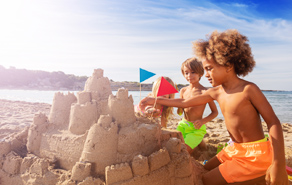 Kindjes bouwen een zandkasteel op het strand